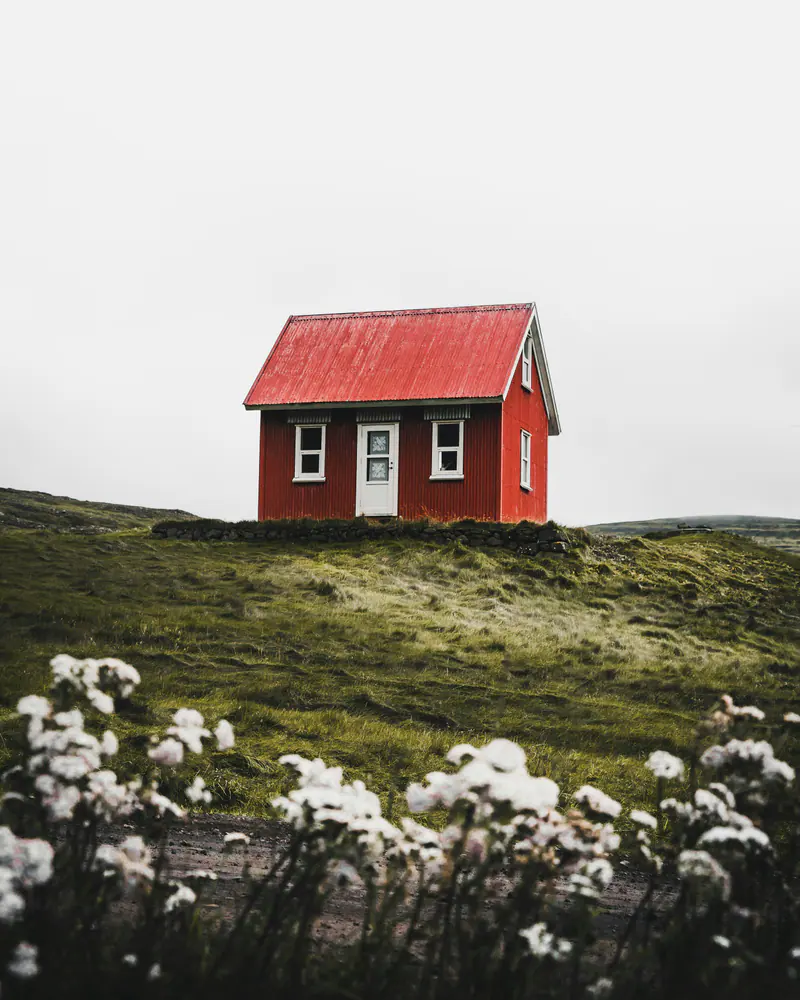 Casa con cubierta de chapa roja sobre una loma verde